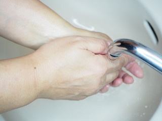 ウイルス感染予防の手洗いの後、手を流水でよくすすぐ様子
