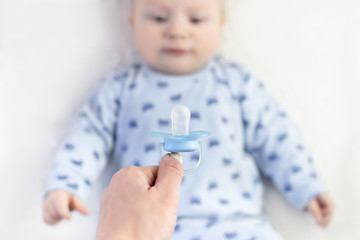 mom gives a pacifier to her little baby. close-up