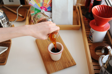 Manual brewing still life. Pouring filter coffee from decanter into cup. Bamboo board. Third wave...