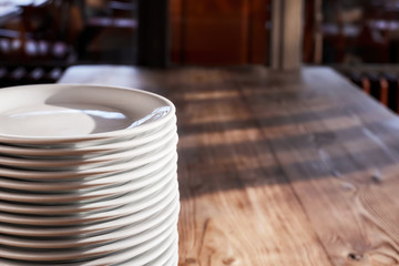 Pile of white plates on the wooden table of a restaurant or cafe