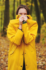 Porait girl in a yellow raincoat in the autumn forest.