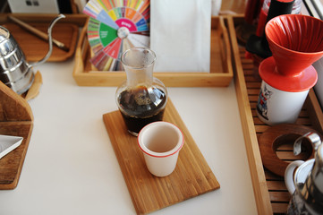 Black filter coffee is served in glass decanter with cup on wooden tray. Manual brewing third wave...