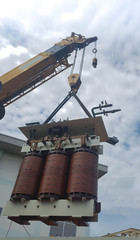 Industrial Crane operating and lifting an electric Transformer