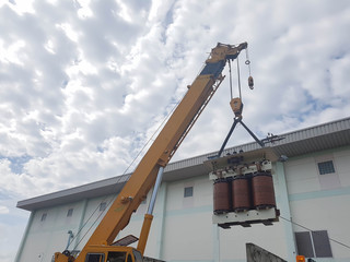 Industrial Crane operating and lifting an electric Transformer