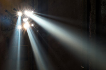 A sunbeam shines through the holes in the iron door. Horizontally. Targeted direct rays of light pass through the fog and create the effect of a multiple spotlight.