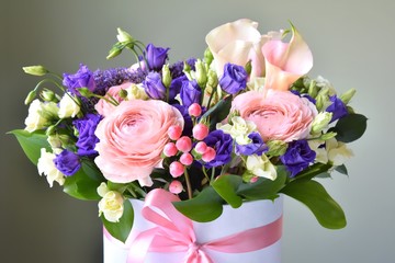 Amazing tender bouquet with pink ranunculus, violet Alstroemeria flowers and tiny white roses in cardboard box with pink ribbon. Beautiful bunch of spring flowers. Easter gift. Seasonal spring flowers