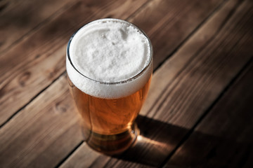 Glass of cold beer on the wooden table of a pub - obrazy, fototapety, plakaty