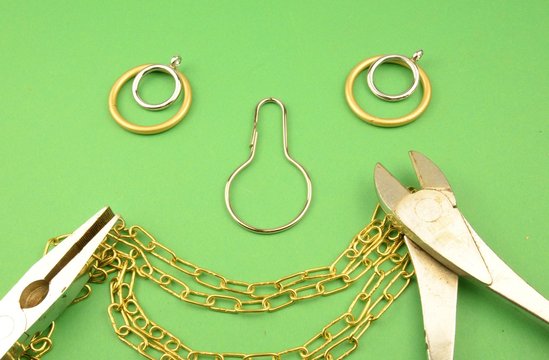 lavorare il metallo: pinza, tronchesevari ma e faccina sorridente fatta con anelli, ganci e catene in vari metalli