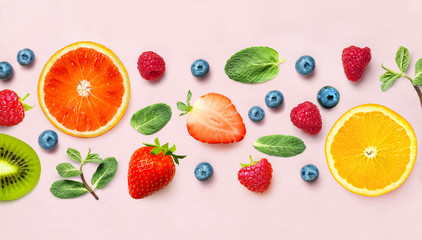 Fresh berry and fruit mix border frame banner of various ripe berries and mint leaves on pink background. Flat lay. Fruit pattern