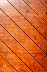 Old wooden boards painted with orange paint form a herringbone pattern, wood texture.