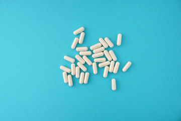 White pharmaceutical medicine capsules on blue background.Medical, pharmacy and healthcare concept. Copy space for your text