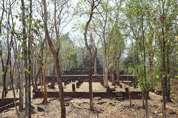 Fototapeta na wymiar Ruins of Ancient Thai Temple (Wat Chedi Kao Yod). Trees grow between ancient stones. Si Satchanalai historical park, Northern Thailand.