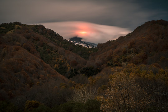 Volcano Etna eruption at night, full moon illuminating the landscape, Bove Valley, Sicily.