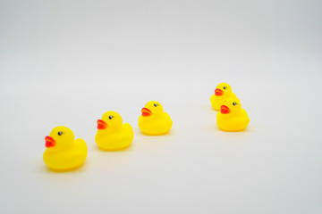 Five mini yellow rubber ducks in a row. One duck out of line. Ge