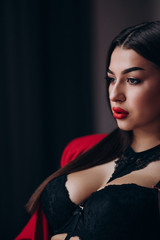 a young girl with dark hair, brown eyes and bright red lips poses in a Studio in a red pantsuit