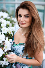 young girl with green eyes admires blooming azaleas in a botanical garden. Closeup of butiful girl with flowers
