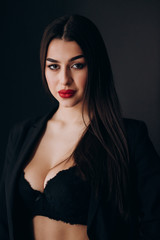 a young girl with dark hair, brown eyes and bright red lips poses in a Studio in a black pantsuit