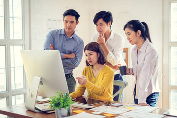 Group of young asian designer in smart casual wear talking and development ux app on mobile phone during the meeting in office.