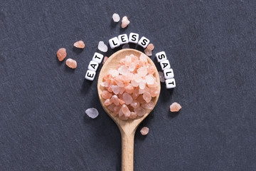 Eat less salt concept to decrease blood pressure hypertension with spoon and crystals on granite...