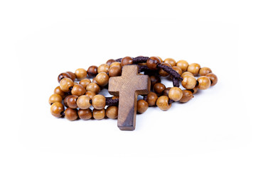 Brown wooden christian rosary curled up, christianity religious symbols isolated on white. Cross symbol in the middle. Chaplet of Divine Mercy prayer conept. Faith, belief. Studio shot