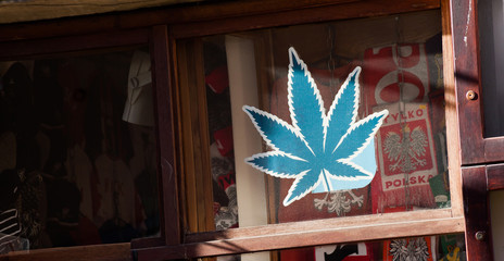 Fototapeta na wymiar Cracow, Małopolska / Poland - circa January 2019: Shop selling cannabis marijuana supplies in Krakow. Store front, window with a green leaf symbol. Medical hemp usage, legalization, legal market