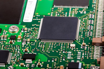 Complex electronics, green circuit board with a microcontroller, microprocessor control chip in the middle, extreme closeup detail macro, technology engineering abstract circuits industrial background