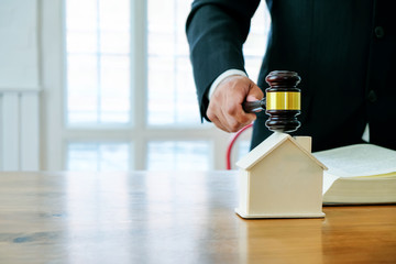 Image of lawyer holding a auction hammer on model house. Concept of the law is to buy or sell houses and land, mortgage.