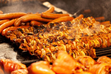 Lots of hot tasty shashlik, sausages and meat on outdoors grill barbecue. Cooking different kinds of meat, bbq concept. Smoke above, food photography, center focus, warm colors. Macro, closeup