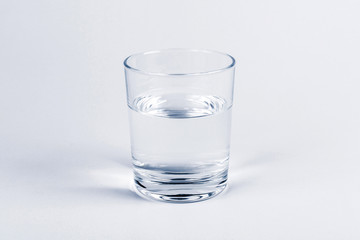 One simple half full half empty glass of fresh crystal clear clean drinking water, solo object...