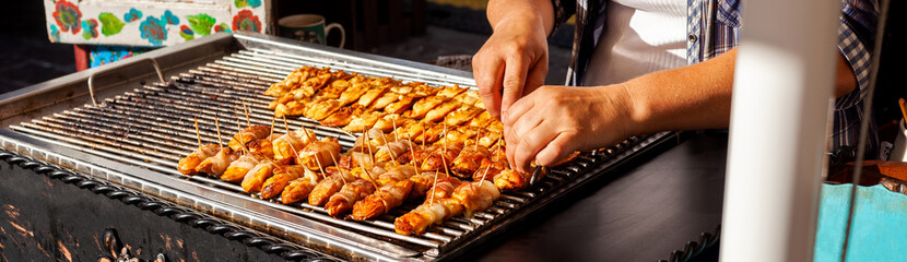 Woman preparing lots of traditional variation on Polish oscypek with melted cheese and bacon on an outside grill, bbq being made. Street food simple warm delicious traditional regional meat