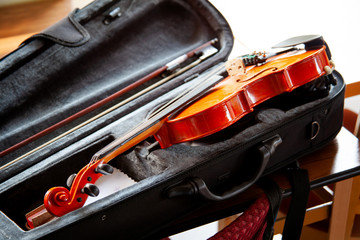 Violin with a bow laying in an open black fiddle case on the table. Classical musical string...