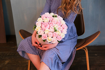a girl in a blue dress and white sneakers is sitting with a bouquet of roses