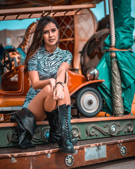 Fototapeta na wymiar Street style, portrait of a young brunette in a carousel with leather boots and skirt