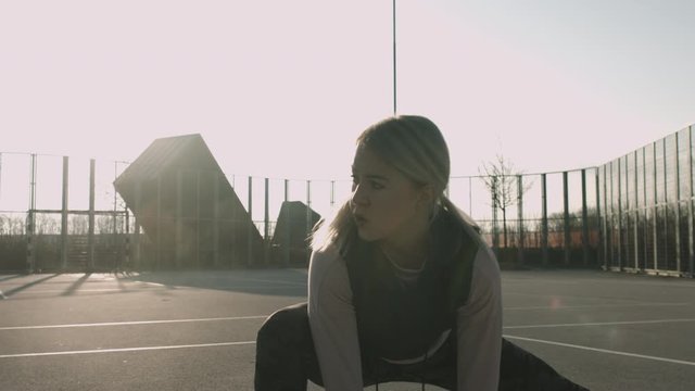 Athletic woman doing side lunges on a fenced court in residential area. Shot in slow motion early in the morning at sunrise.