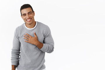 Happy and pleased, flattered hispanic man thanking for praises, holding hand on chest and smiling...
