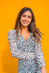 A pretty brunette smiling with a yellow background behind