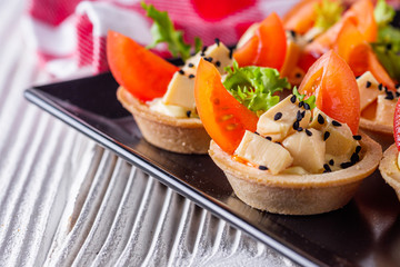 delicious snack tartlets on rustic wooden background