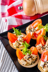 delicious snack tartlets on rustic wooden background
