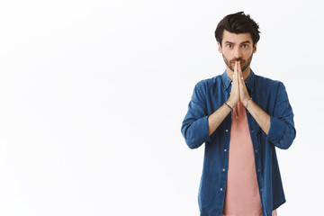 Handsome young bearded guy begging for permission or favor, asking help as clasp hands together...