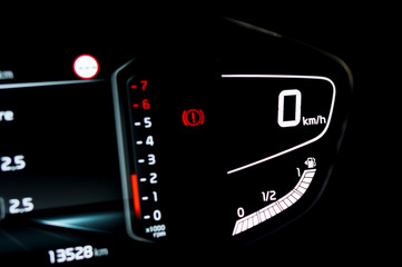 Close up of side view of illuminated full digital car dashboard panel with speedometer, tachometer, odometer and fuel level gauge in hybrid vehicle. Modern electronic instrument cluster in modern car.