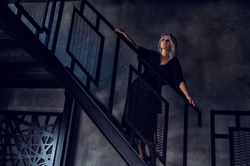 girl in a black dress dressing gown stands on the stairs in the house