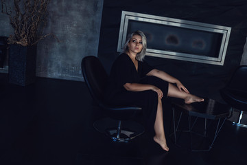 girl in a black dress dressing gown sitting in a house in a dark interior