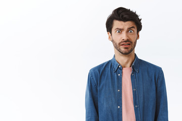 Freak-out shocked handsome bearded man, cringe from something disgusting or awful, grimacing alarmed, frowning make troubled, frustrated expression, standing worried over white background - obrazy, fototapety, plakaty