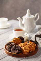 Set of different cookies in a plate and tea on a wooden background.
