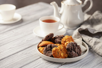 Set of different cookies in a plate and tea on a wooden background.