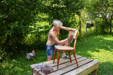 woman in yard restores an old chair
