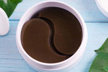 Cosmetics collagen brown patches in a plastic jar for skin around the eyes on a light blue wooden...