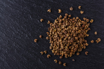 Sichuan pepper on a dark stone background