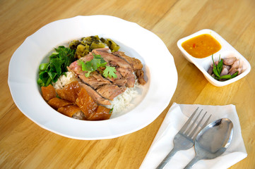 Stewed leg pork without fat in white dish and sour chili sauce with fresh chili and garlic in white bowl on wooden table