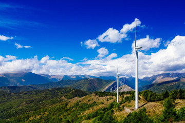 Aerial view of wind turbine farm. Wind power plants in green summer landscape with clouds.